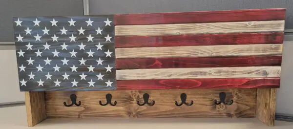 A wooden american flag with hooks on it.